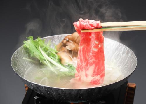 a piece of meat and vegetables in a bowl with chopsticks at Suimeikan in Gero