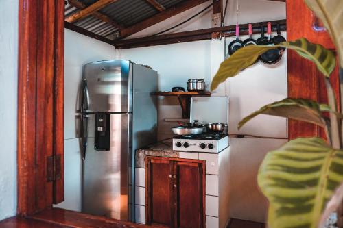 a kitchen with a refrigerator and a stove at Hostal Los Chamos in San Juan del Sur