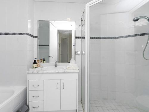 a white bathroom with a sink and a shower at Crystal Waters Unit 11 in The Entrance