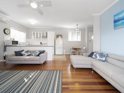 a living room with two couches and a kitchen at Eloora House Blue bay in Long Jetty