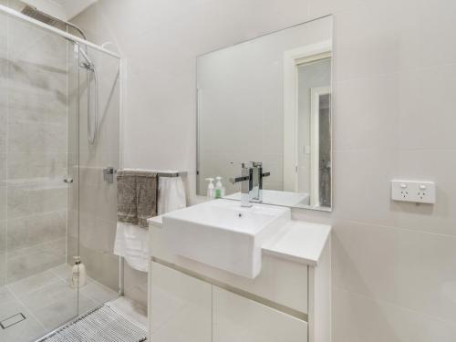 uma casa de banho branca com um lavatório e um chuveiro em Lakedge Home em Berkeley Vale