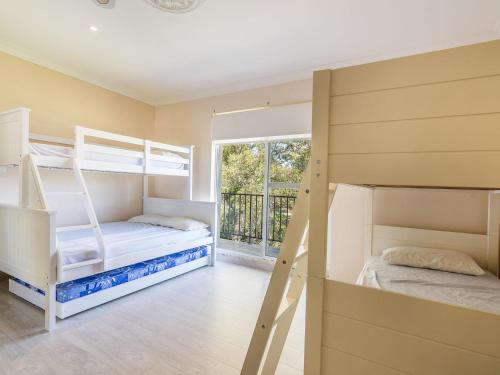 a bedroom with two bunk beds and a window at Lakeshore Apartments Unit 5 in The Entrance