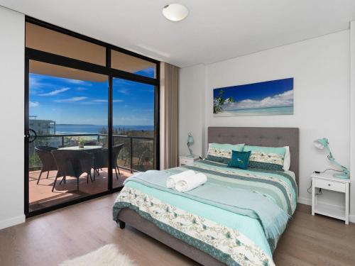 a bedroom with a bed and a balcony with a table at Crystal Waters Unit 11 in The Entrance