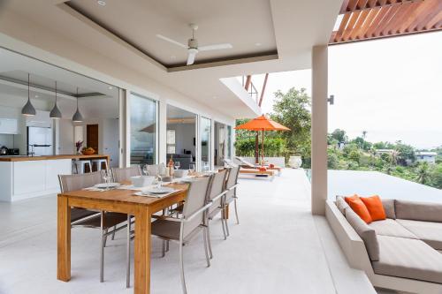 an open kitchen and dining room with a wooden table and chairs at Bay Villas Koh Phangan in Salad Beach