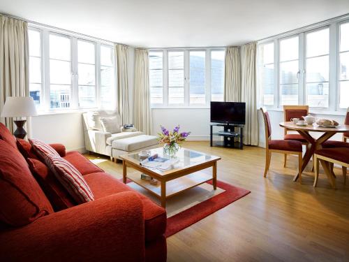 ein Wohnzimmer mit einem roten Sofa und einem Tisch in der Unterkunft Marlin Apartments London City - Queen Street in London