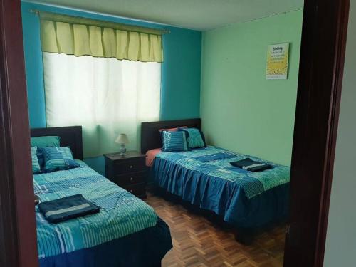 Duas camas num quarto com paredes azuis em Amplio y cómodo departamento. em Loja