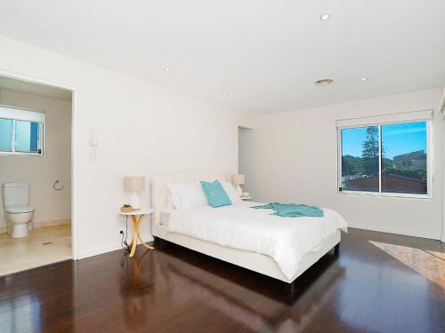 a white bedroom with a bed and a window at Perfect Beach Front Duplex - The Entrance North in The Entrance