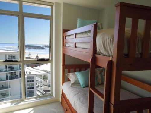 a bedroom with bunk beds and a large window at Ocean Views Sundrift Unit 26 in The Entrance