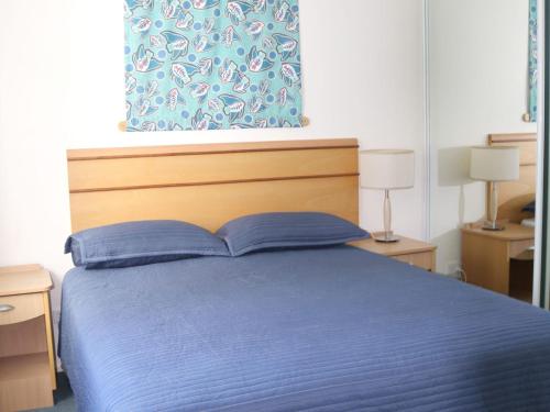Un dormitorio con una cama azul y una ventana. en The Entrance Waterfront Resort Unit 502, en The Entrance