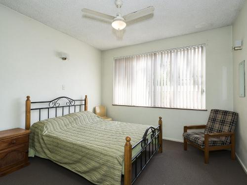 Un dormitorio con una cama y una silla y una ventana. en The Sands Unit 5, en The Entrance