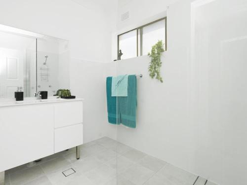 a white bathroom with a sink and a blue towel at Waterfront Unit 2 in The Entrance
