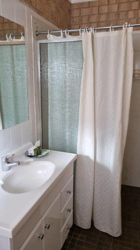 a bathroom with a sink and a white shower curtain at Lone Pine Motel in Corowa