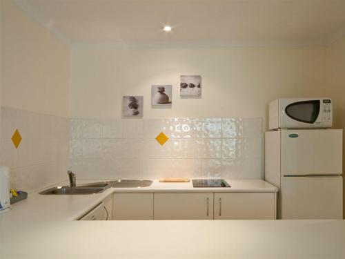 a kitchen with a refrigerator, microwave, sink and dishwasher at Mango House Resort in Airlie Beach