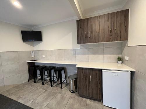 a kitchen with wooden cabinets and bar stools at Ryley Motor Inn in Wangaratta