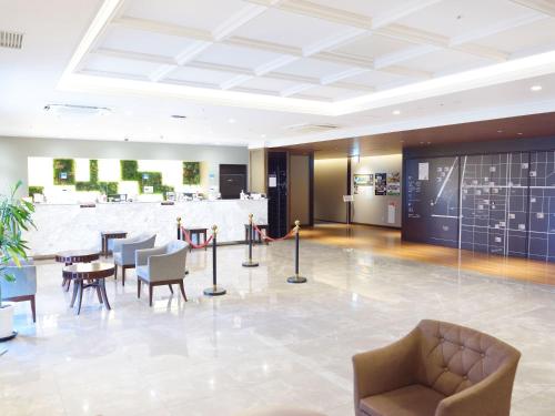 a lobby with tables and chairs in a building at Hotel Abest Grande Okayama in Okayama