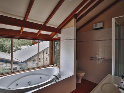 ein Bad mit einer Badewanne und einem Fenster in der Unterkunft Edzell Stunning Waterfront Home in Jindabyne
