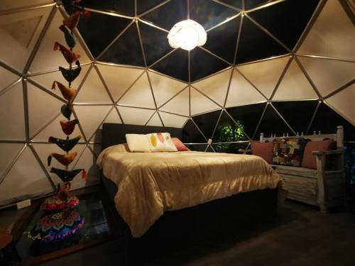 1 dormitorio con 1 cama en una pared triangular en Fantasia Glamping, en Bogotá
