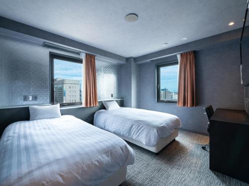um quarto de hotel com duas camas e duas janelas em EN HOTEL Hamamatsu em Hamamatsu