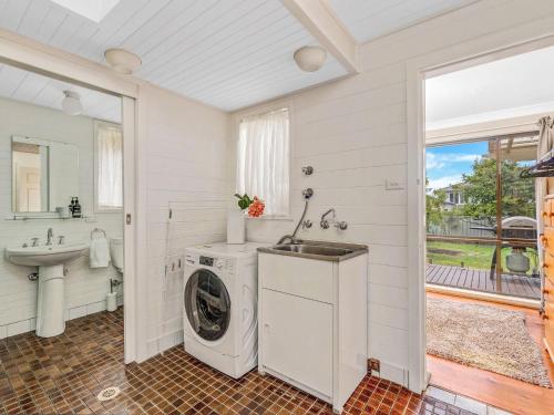 a bathroom with a washing machine and a sink at The Golden Ticket by Experience Jervis Bay in Vincentia