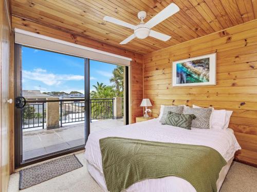 1 dormitorio con 1 cama, ventilador de techo y balcón en The Golden Ticket by Experience Jervis Bay, en Vincentia