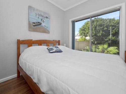 ein Schlafzimmer mit einem Bett und einem großen Fenster in der Unterkunft Eloora House Blue bay in Long Jetty