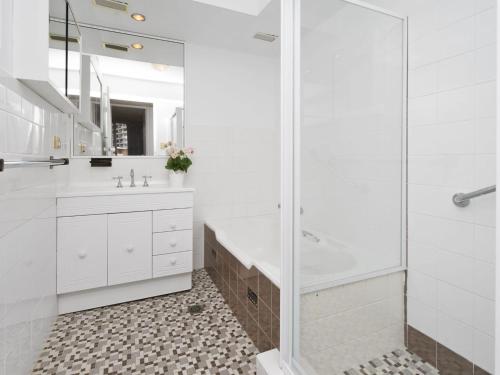 a white bathroom with a shower and a sink at Tasman Towers Unit 13 in The Entrance