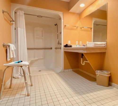 La salle de bains est pourvue d'une douche et de carrelage blanc. dans l'établissement Days Inn by Wyndham Roseburg, à Roseburg