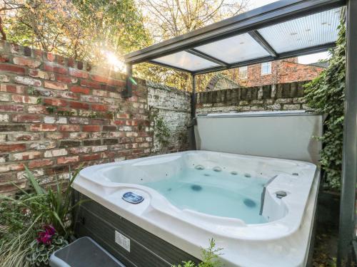 een bad in een achtertuin met een bakstenen muur bij Baggergate House in York