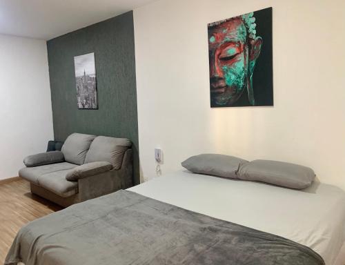 a bedroom with a bed and a couch and a painting at Flat Belvedere com piscina in São Vicente