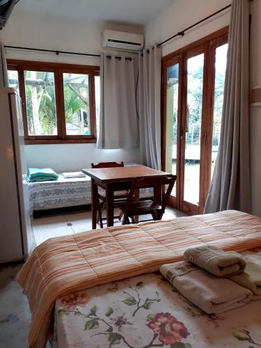 a bedroom with a bed and a table and windows at Pousada Praia Verde in Imbituba