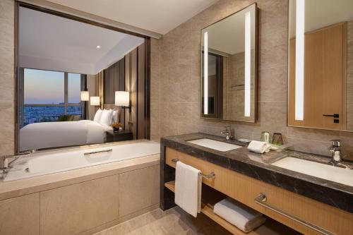La salle de bains est pourvue de 2 lavabos, d'une baignoire et d'un lit. dans l'établissement Holiday Inn & Suites Langfang New Chaoyang, an IHG Hotel, à Langfang
