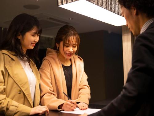 two women sitting at a table signing a document at HOTEL U's 香櫨園 in Nishinomiya