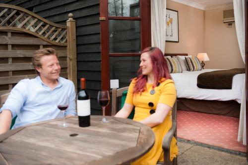 a man and a woman sitting at a table with a bottle of wine at Ellington Lodge at The Concorde in Eastleigh