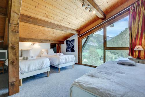 une chambre avec deux lits et une grande fenêtre dans l'établissement Chalet Madeleine - Snow and Trek, à Morzine