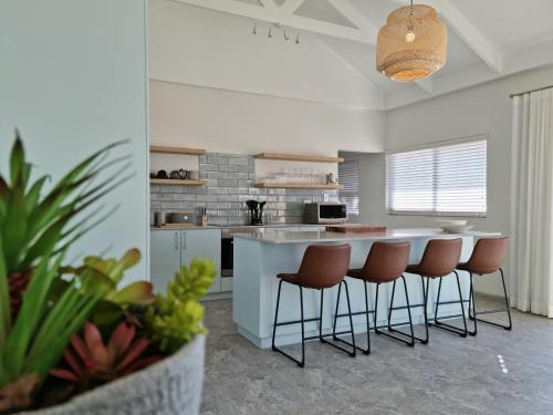 uma cozinha com um balcão e bancos num quarto em The Anchor, Luxury living for 2 with sea view and Jacuzzi em Gordonʼs Bay