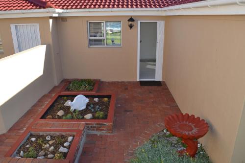a patio with two flower beds in front of a house at Hermanus Beach Club - Le Maree House 18 in Hermanus