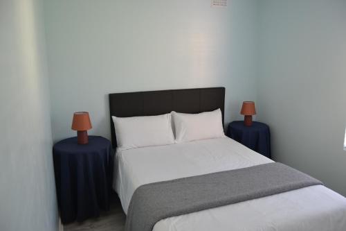 a bedroom with a bed with two blue tables at Hermanus Beach Club - Le Maree House 18 in Hermanus