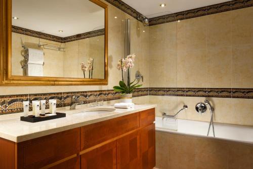 a bathroom with a sink and a mirror and a tub at Swiss Diamond Hotel & Spa in Morcote