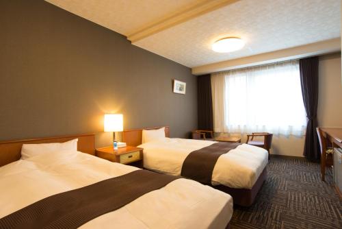 a hotel room with two beds and a window at Hotel Hachiman in Hachiman
