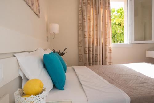 a bedroom with a bed with blue pillows and a window at Blue Sky Apartments in Malia