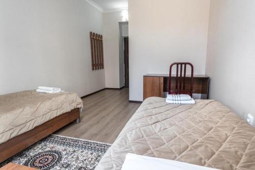 a bedroom with two beds and a desk in it at Muras Hotel Karakol in Karakol