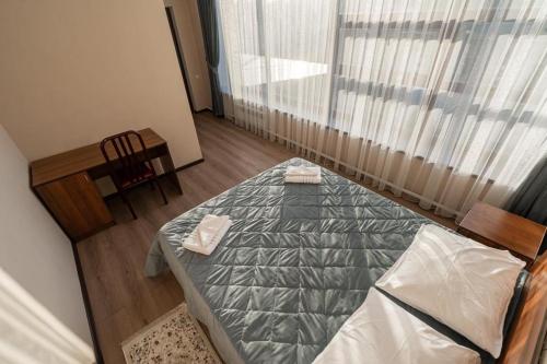 a bedroom with a bed and a chair and a window at Muras Hotel Karakol in Karakol
