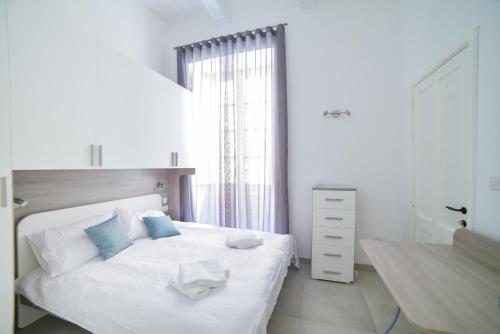 a bedroom with a white bed with blue pillows at CA1- City Central Apartment 1 in Valletta
