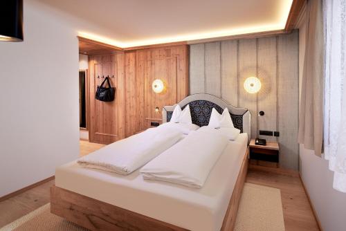 a bedroom with a large white bed with white pillows at Hotel Neue Post in Mayrhofen