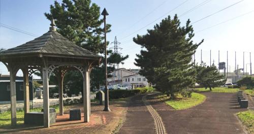 a gazebo next to a road with a tree at Tama Hotel in Ishinomaki