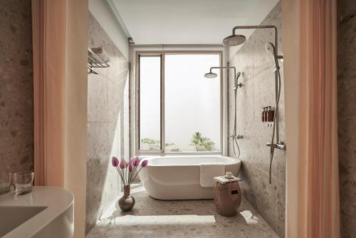 a bathroom with a bath tub and a window at Le Récit Boutique Hôtel de Dalat in Da Lat