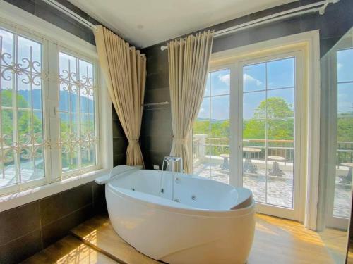 a large bathroom with a tub in front of windows at Biệt Thự Con Công Sóc Sơn Venuestay in Phú Hữu