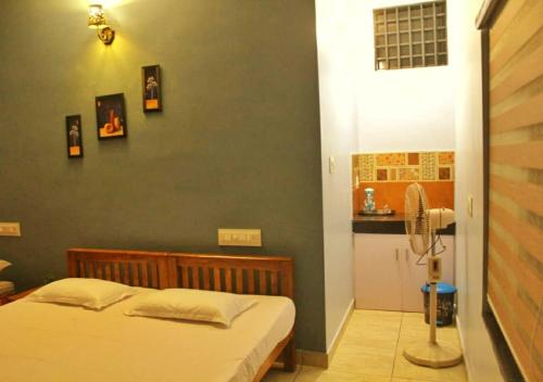 a bedroom with a bed and a kitchen with a fan at High Island Homestay in Cochin