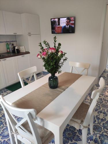 a white dining room table with a vase of flowers on it at B&B Verde Smeraldo in Santa Maria La Carità