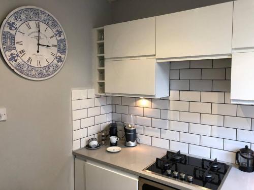 a kitchen with a clock on the wall above a stove at Remarkable Apartment near London Tower Bridge in London